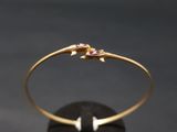 un bracelet rigide en or orné de pierres roses sur un fond noir