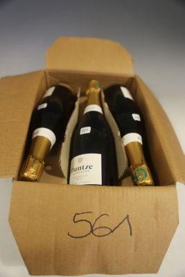 trois bouteilles de vin dans un carton sur une table