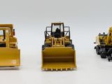 three construction vehicles that are lined up on a white surface