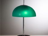 la lampe verte repose sur un socle noir posé sur une table blanche