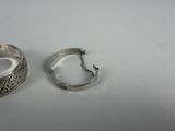 pair of silver bracelets on a white surface with a chain
