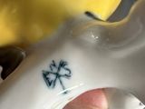 a hand that is holding a ceramic object with a cross on it