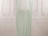 the back of a dress on a mannequin stand in front of a white wall