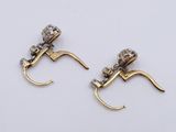 two pairs of gold and diamond earrings on a white surface