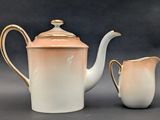 a white tea pot and a creamer sitting next to each other