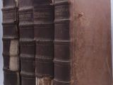 trois vieux livres sont empilés sur une surface blanche