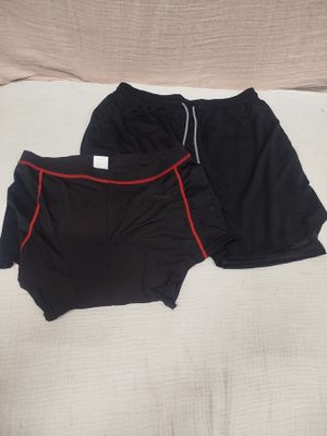 two pairs of black and red shorts laying on a bed