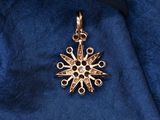 a close up of a gold snowflake pendant on a blue cloth