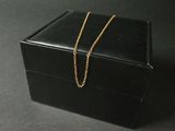 une petite boîte noire à laquelle est attachée une chaîne en or