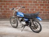 a blue and black motorcycle parked in front of a brick wall