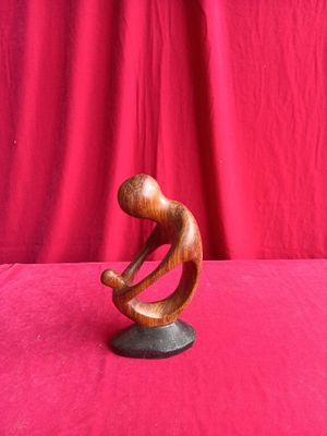 a wooden sculpture of a man sitting on top of a rock