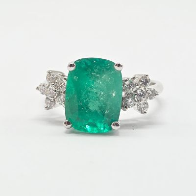 gros plan d'une bague avec une pierre verte entourée de diamants