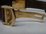 un gros plan d'une montre en or avec un bracelet en cuir marron