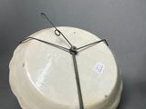 a white plate with a wire around it on a gray surface