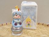 a small figurine of a little girl in a snow suit sitting next to a box