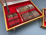 des couverts dans un coffret en bois avec une doublure rouge sur un fond bleu