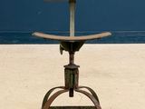 a wooden seat on a metal stool in front of a blue wall