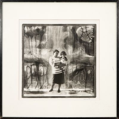 photographie en noir et blanc encadrée représentant une femme tenant un enfant dans ses bras devant un tableau