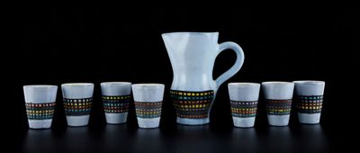 un pichet et six tasses posés les uns à côté des autres sur une table