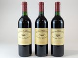trois bouteilles de vin rouge posées sur une table blanche