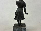 statue of a woman in a dress and hat on a marble base