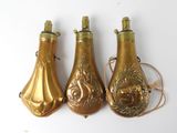 three gold colored bottles with designs on them sitting next to each other