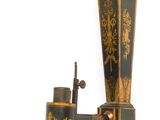 une lampe murale noire et dorée surmontée d'une statue