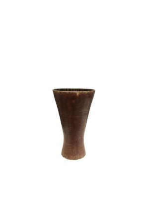 un vase brun posé sur une surface blanche