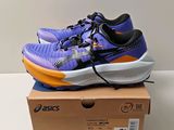 des chaussures de course violettes et orange posées sur une boîte, elle-même posée sur une table