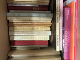 many books in a box that are stacked on top of each other