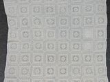 une couverture blanche au crochet posée sur une surface noire