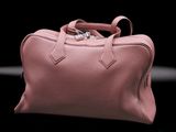 a picture of a pink leather bag on a black background