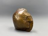 une vieille tête d'homme en bronze posée sur un fond blanc