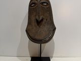an image of a wooden mask on a stand against a white wall