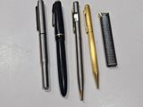 trois stylos et un peigne sont posés sur une surface blanche