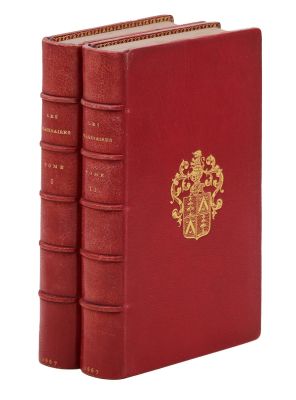 trois livres rouges ornés d'emblèmes dorés, posés sur une surface blanche