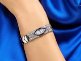a close up of a woman ' s hand wearing a blue dress and a diamond bracelet