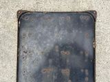 a square metal plate with holes on it on the ground