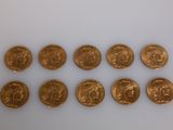 a group of six gold sovereigns on a white surface