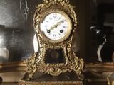 a gold clock sitting on top of a shelf next to vases