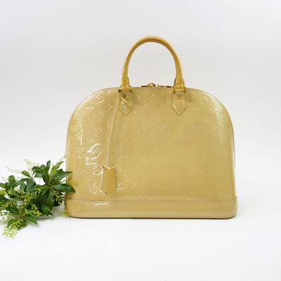 yellow louis vuitton handbag with green plant on white background