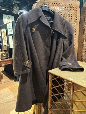 manteau en laine exposé dans un magasin, avec une chaise en arrière-plan
