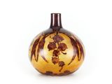 un vase orange et marron posé sur une surface blanche