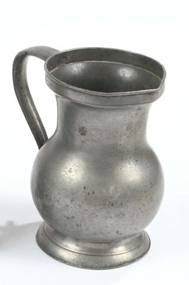 a silver pitcher sitting on a table next to a white background