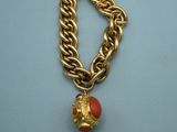 an image of a gold chain bracelet with a red bead on it