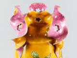 a yellow vase with pink flowers on it on a table