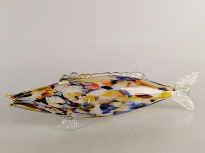 sculpture représentant un poisson en verre jaune et bleu posée sur une surface blanche