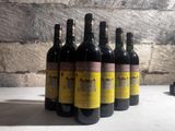 six bottles of wine are lined up on a table in front of a brick wall