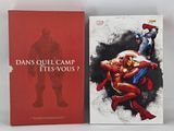 two books on a white table with a red cover and a black and white drawing of a superhero