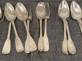tout un tas de cuillères en argent et de petites cuillères posées sur une table
